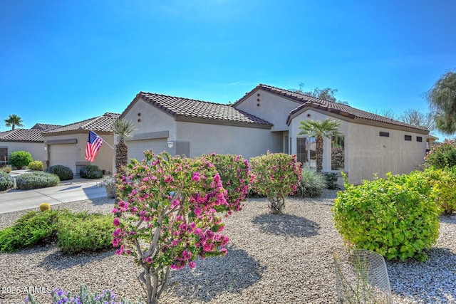 mediterranean / spanish-style home featuring an attached garage, a tile roof, and stucco siding