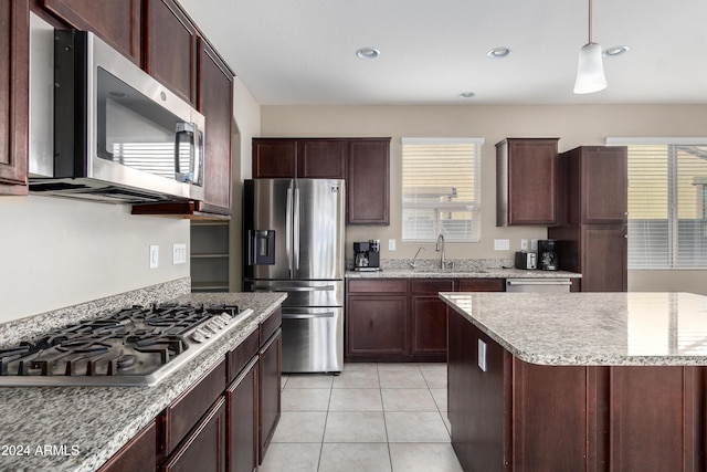 kitchen featuring dark brown cabinetry, sink, hanging light fixtures, light tile patterned flooring, and appliances with stainless steel finishes