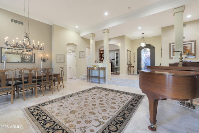 interior space featuring decorative columns, an inviting chandelier, and ornamental molding