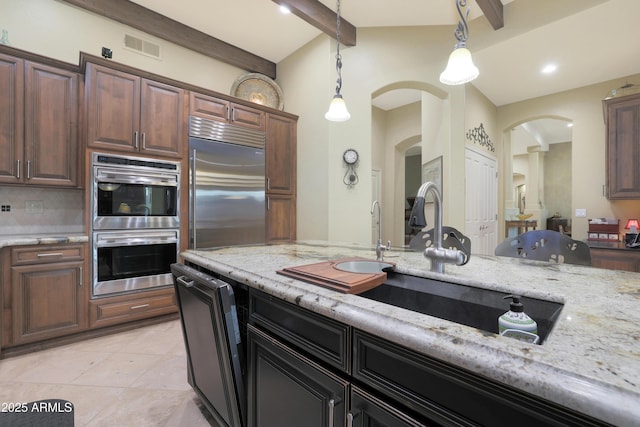 kitchen featuring hanging light fixtures, tasteful backsplash, beam ceiling, light stone counters, and stainless steel appliances