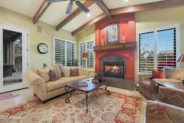 living room with vaulted ceiling with beams, ceiling fan, a healthy amount of sunlight, and a tiled fireplace