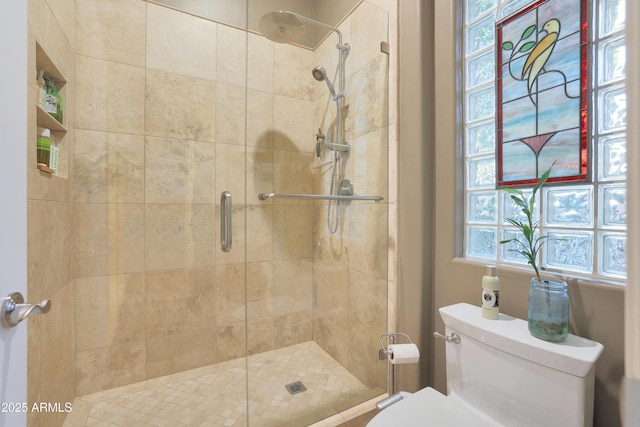 bathroom featuring toilet and a shower with shower door