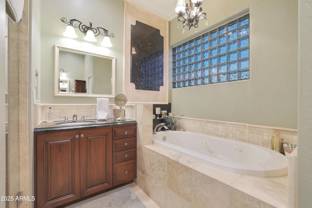 bathroom featuring a notable chandelier, vanity, and tiled bath