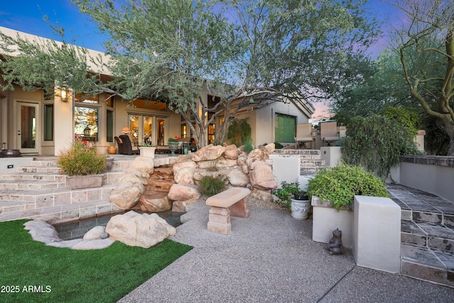 yard at dusk with french doors and a patio area