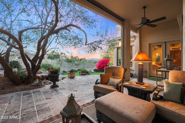 patio terrace at dusk featuring ceiling fan and an outdoor living space