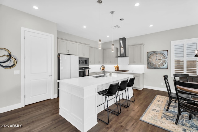 11233 N Blakely St, Surprise, AZ 85388 - kitchen with wall chimney range hood, a sink, stainless steel appliances, a breakfast bar area, and dark wood-style flooring
