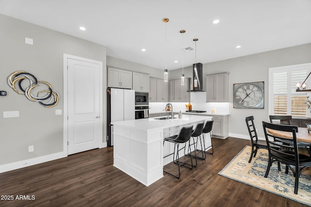11233 N Blakely St, Surprise, AZ 85388 - kitchen featuring stainless steel appliances, a sink, wall chimney range hood, baseboards, and a kitchen bar
