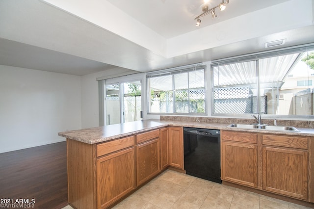 kitchen featuring kitchen peninsula, track lighting, dishwasher, sink, and light tile flooring