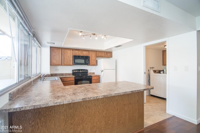 kitchen featuring kitchen peninsula, plenty of natural light, a tray ceiling, and black appliances