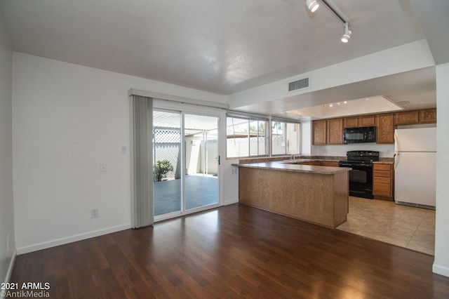 kitchen with track lighting, kitchen peninsula, black appliances, and dark hardwood / wood-style flooring
