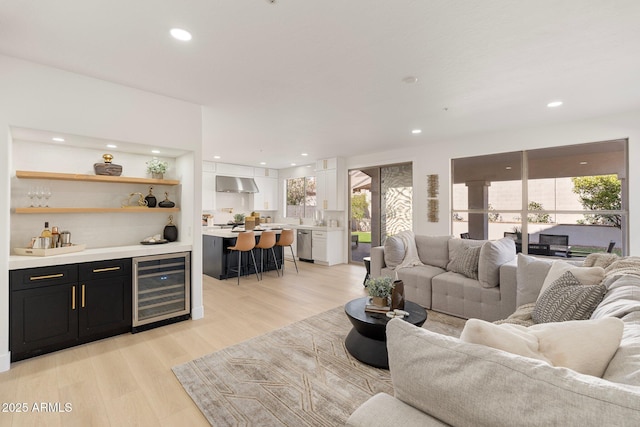 living room with bar, wine cooler, and light hardwood / wood-style flooring