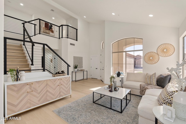 living room featuring a towering ceiling and light hardwood / wood-style floors