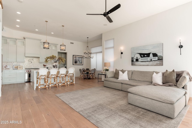 living room with recessed lighting, ceiling fan, light wood-style flooring, and a chandelier