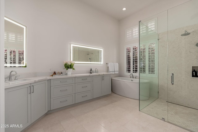 bathroom with a shower stall, a freestanding bath, double vanity, and a high ceiling