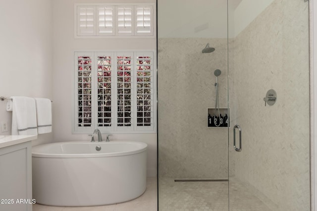 bathroom featuring tiled shower, a soaking tub, vanity, and tile patterned flooring