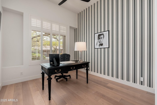 office area featuring baseboards, ceiling fan, light wood-type flooring, wallpapered walls, and an accent wall