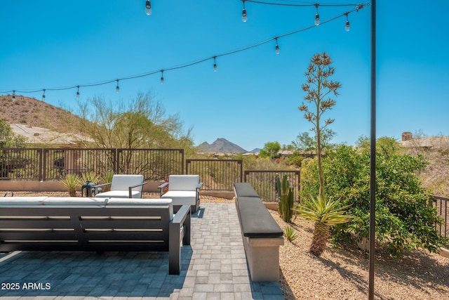 view of patio with an outdoor living space, a mountain view, and fence