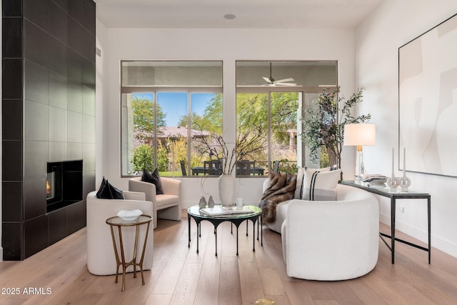 living room with a fireplace, healthy amount of natural light, ceiling fan, and wood finished floors