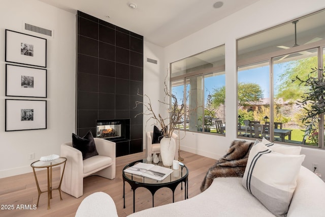 living room with a multi sided fireplace, light wood finished floors, baseboards, and healthy amount of natural light