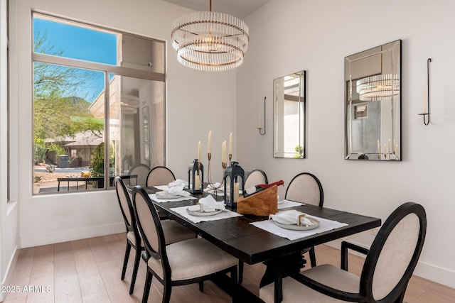 dining room featuring baseboards, a chandelier, and light wood-style floors