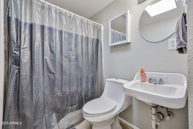 11815 N 112th Dr, Youngtown, AZ 85363 - bathroom with toilet, a textured wall, a sink, a shower with shower curtain, and baseboards