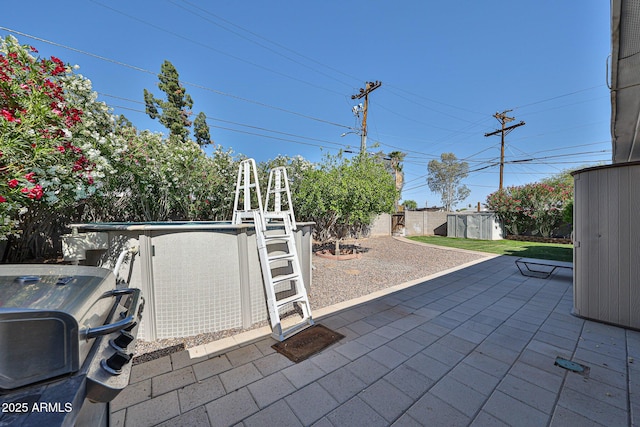11815 N 112th Dr, Youngtown, AZ 85363 - view of patio / terrace featuring a fenced backyard, a storage unit, an outdoor pool, area for grilling, and an outbuilding