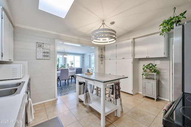 11815 N 112th Dr, Youngtown, AZ 85363 - kitchen with white microwave, a chandelier, black electric range, white cabinets, and light tile patterned flooring