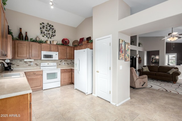 kitchen with white appliances, sink, backsplash, high vaulted ceiling, and ceiling fan