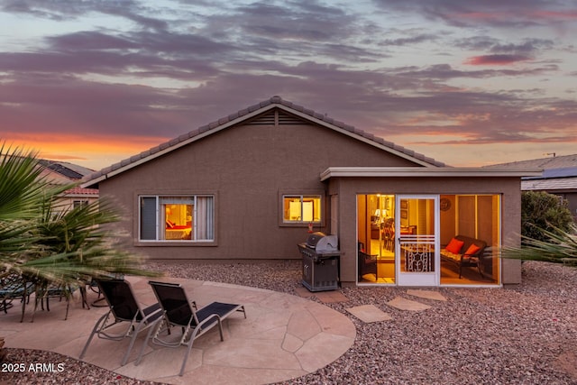 back house at dusk featuring a patio area