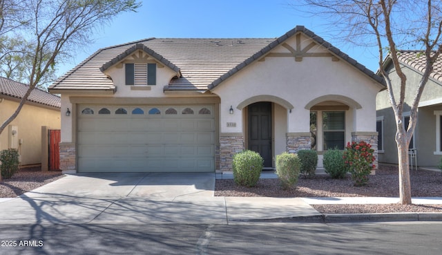 view of front of home featuring driveway, stone siding, a tile roof, and a garage