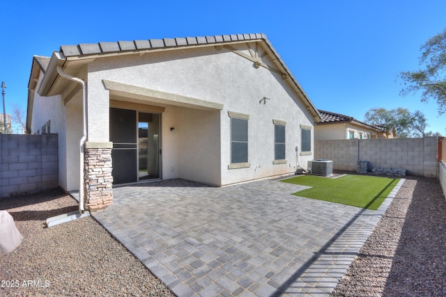 rear view of house with cooling unit, a patio area, a fenced backyard, and stucco siding