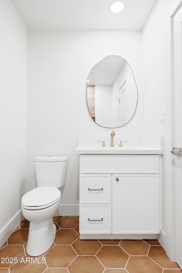 bathroom featuring baseboards, vanity, toilet, tile patterned floors, and recessed lighting
