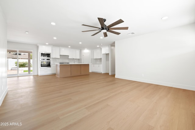 unfurnished living room featuring a ceiling fan, light wood-type flooring, baseboards, recessed lighting, and a sink