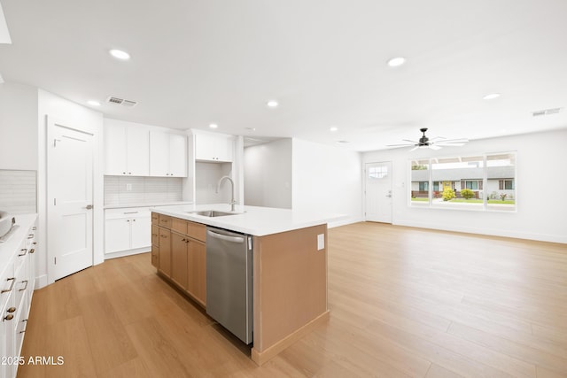 kitchen with a sink, dishwasher, light wood-style floors, ceiling fan, and decorative backsplash