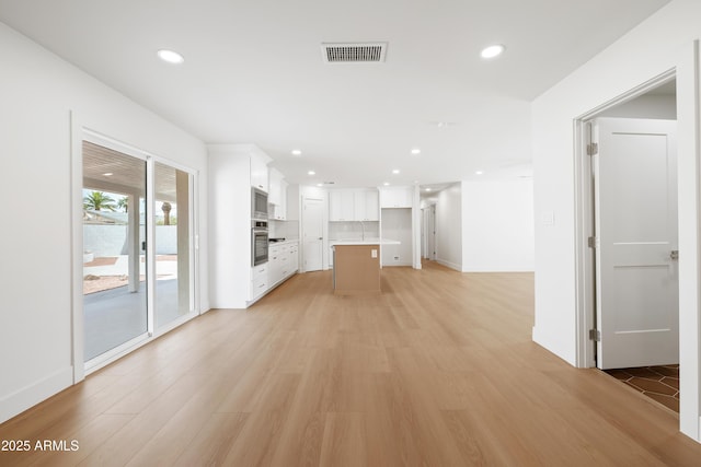 unfurnished living room with light wood finished floors, recessed lighting, and baseboards