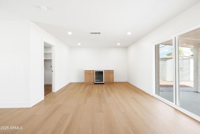 unfurnished living room featuring beverage cooler, light wood-type flooring, baseboards, and recessed lighting