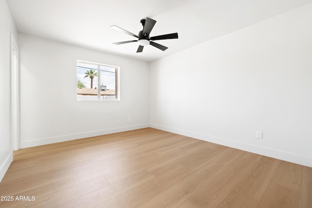 spare room featuring baseboards, light wood-style flooring, and a ceiling fan