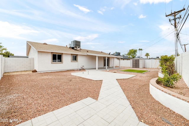 rear view of property with a storage unit, a patio area, cooling unit, a fenced backyard, and an outdoor structure