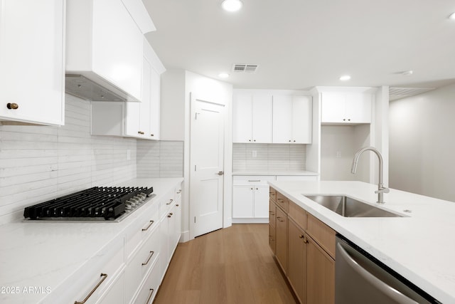 kitchen with stainless steel appliances, a sink, light wood finished floors, light countertops, and recessed lighting