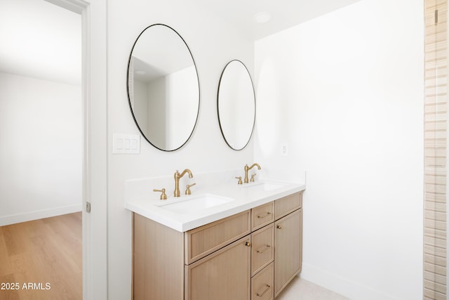 bathroom with double vanity, baseboards, and wood finished floors