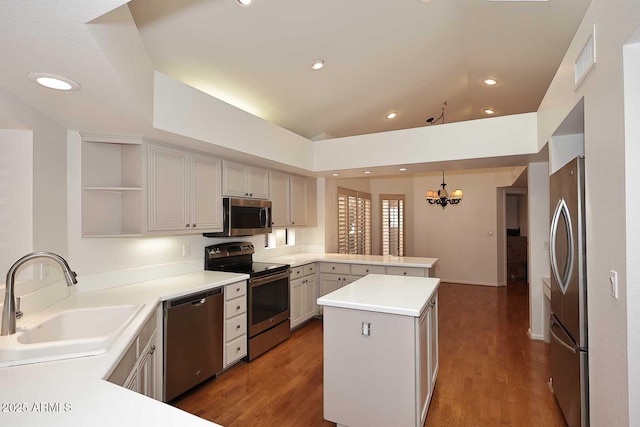 kitchen featuring sink, appliances with stainless steel finishes, a center island, decorative light fixtures, and kitchen peninsula