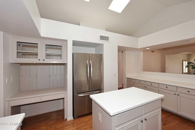 kitchen with hardwood / wood-style flooring, lofted ceiling with skylight, a center island, and stainless steel refrigerator