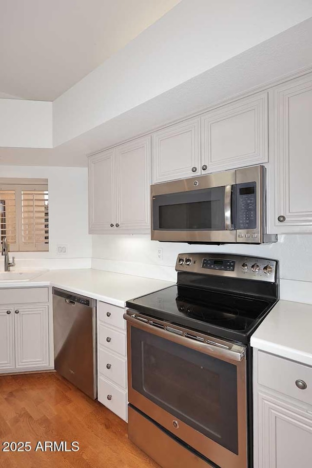 kitchen with white cabinetry, appliances with stainless steel finishes, sink, and light hardwood / wood-style flooring