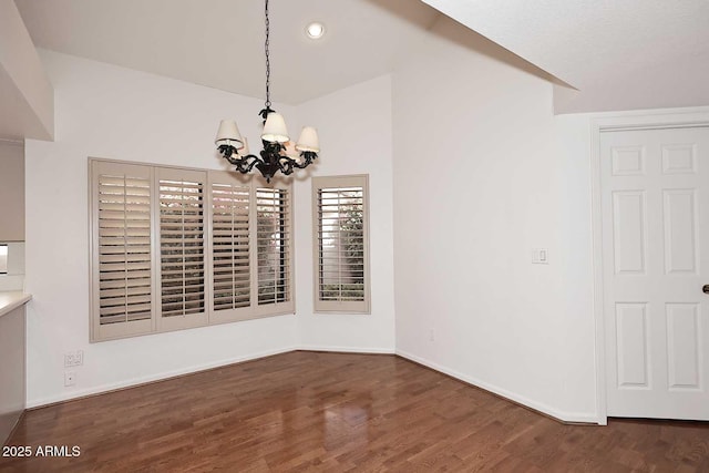 unfurnished dining area featuring dark hardwood / wood-style flooring, a chandelier, and vaulted ceiling