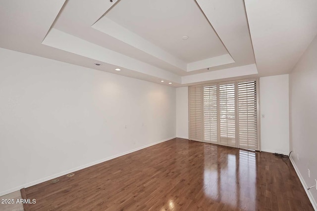 unfurnished room featuring a tray ceiling and dark hardwood / wood-style floors