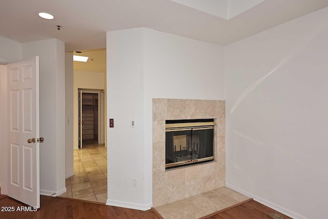 unfurnished living room featuring a tile fireplace and wood-type flooring