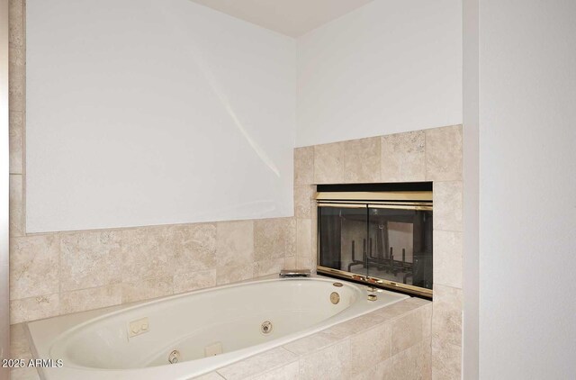 bathroom with tiled tub and a fireplace