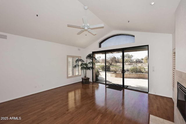 interior space featuring hardwood / wood-style floors, vaulted ceiling, a tile fireplace, and ceiling fan