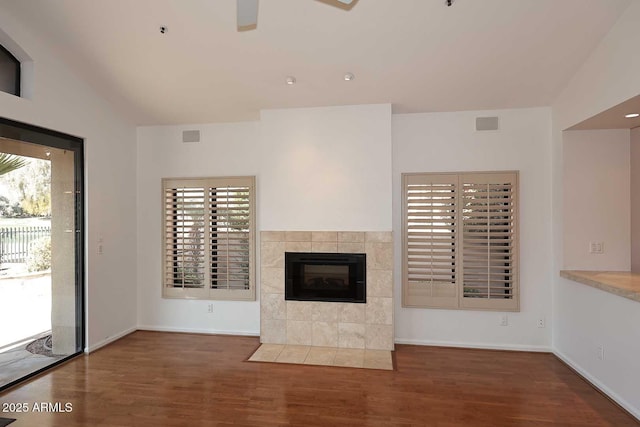 unfurnished living room with ceiling fan, a fireplace, dark hardwood / wood-style floors, and a healthy amount of sunlight