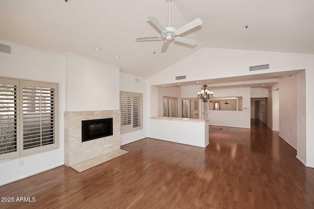 unfurnished living room with a tile fireplace, dark hardwood / wood-style floors, ceiling fan with notable chandelier, and high vaulted ceiling